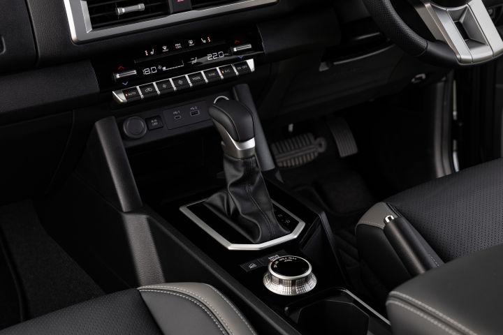 Centre console detail in a 2026 Nissan Navara ST-X, showing the automatic gear selector, drive-mode dial, cupholder, USB ports, and dual-zone climate controls above.