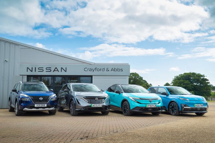 Front view of a Nissan X‑Trail, Ariya, LEAF and MICRA parked outside a dealership building