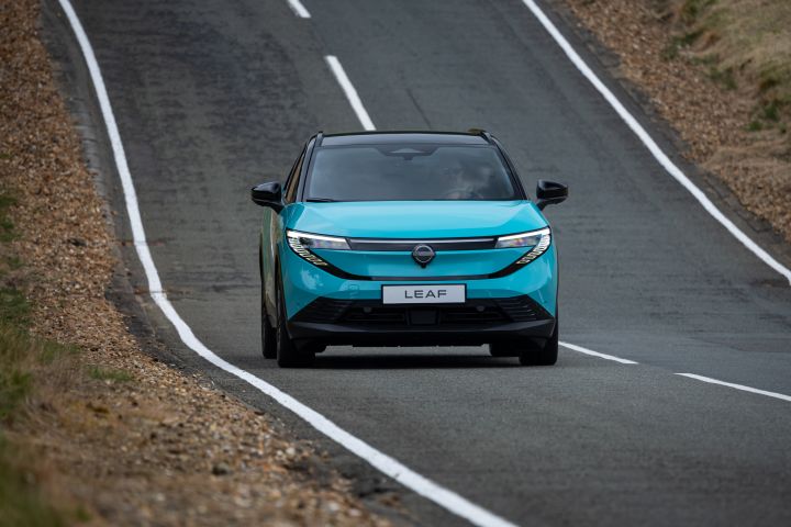 Une nouvelle Nissan LEAF bleu turquoise roule de face sur une route avec des marquages blancs.