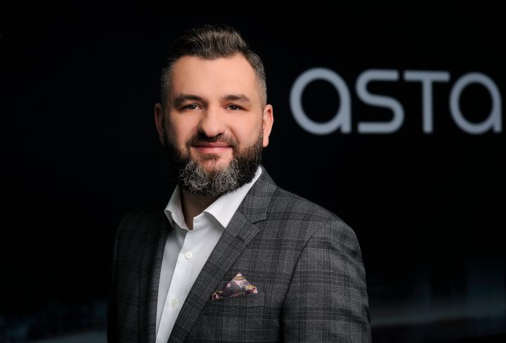 Piotr Laube - dyrektor zarządzający firmy Astara w Polsce z logotypem Astara w tle