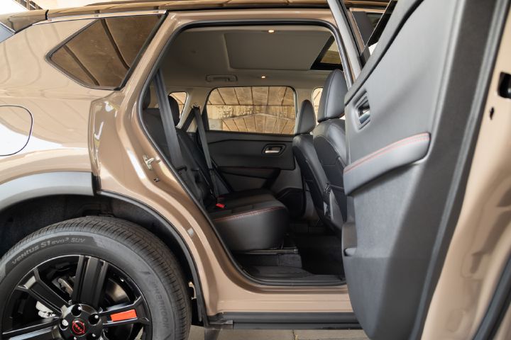 View through the open rear passenger door of a Nissan X‑Trail