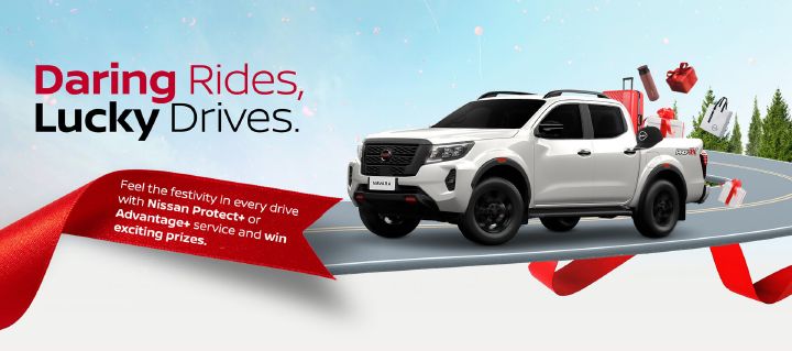 A white Nissan Navara driving along a curved road with holiday-themed gift items in the truck bed, with the campaign headline reading “Daring Rides, Lucky Drives”