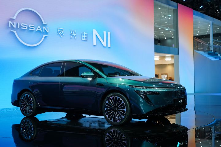 東風日産の緑色の新型セダン電気自動車「N7」。背景に青い電子サインと日産ロゴ、「NI」の文字。