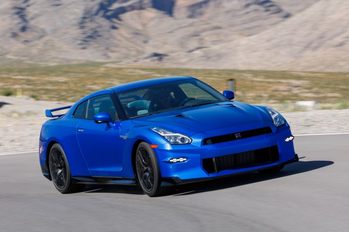 Front 3/4 image of a bue 2024 Nissan GT‑R Special Edition driving on a road with a blurry mountain in the background