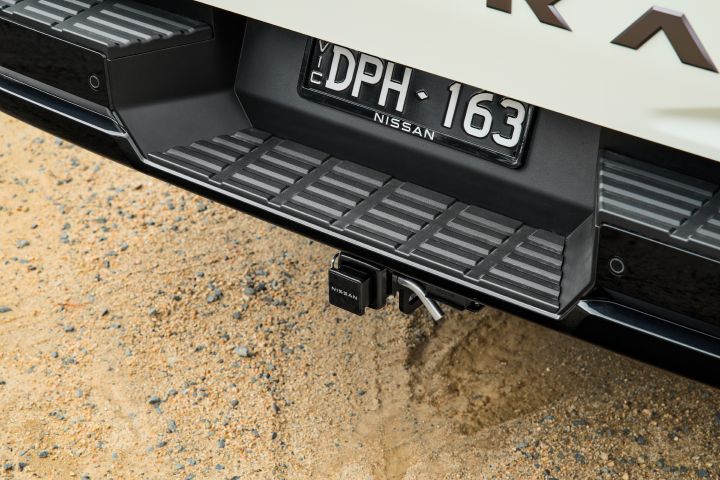 2026 Nissan Navara SL dual cab ute finished in Alpine White shown in a close rear detail of the bumper step, tow hitch receiver and textured loading surface.