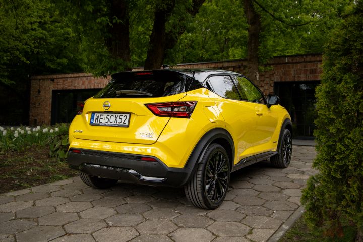 Żółty Nissan Juke stojący tyłem na tle budynku i zieleni