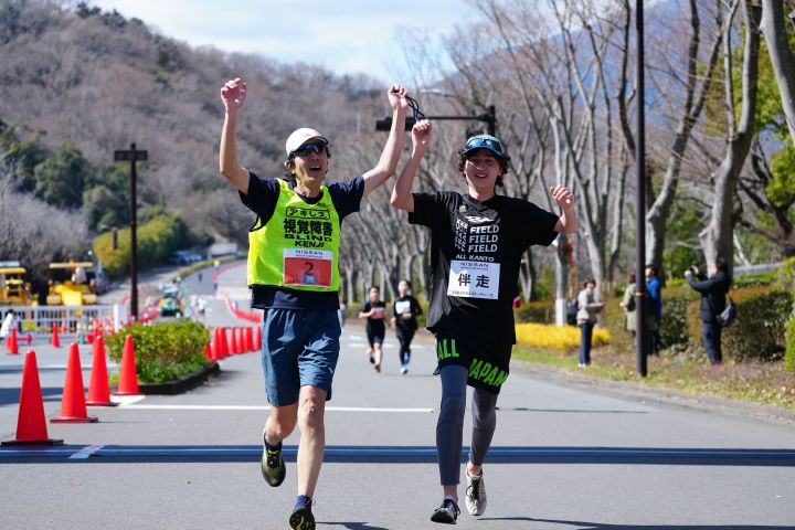 男性の選手と伴走者が笑顔で走っている様子