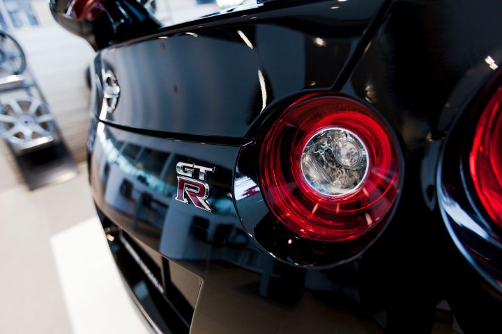 Gros plan de l'arrière d'une Nissan GT‑R noire, en mettant l'accent sur le feu arrière rond et l'insigne « GT‑R ».