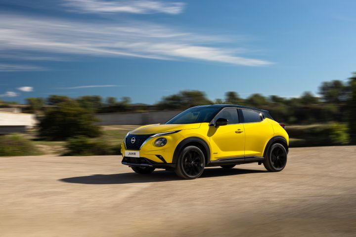 Fahraufnahme gelber Nissan Juke 3/4 Front auf hellem Untergrund im Hintergrund vor grünen Pflanzen und blauem Himmel