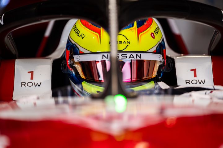 Frontale Nahaufnahme von Oliver Rowland, der vor einer Trainingssession mit heruntergeklapptem Visier in seinem Nissan Formel E Rennwagen sitzt