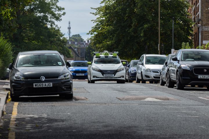 Far away dynamic shot of evolvAD residential route driving amongst parked vehicles