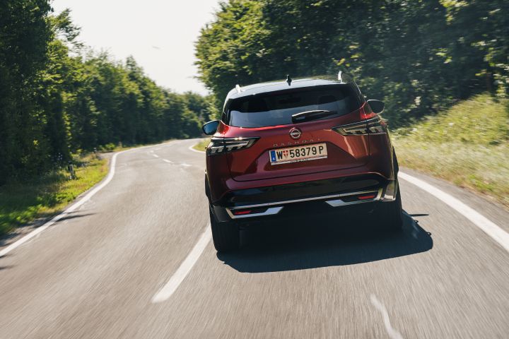 Fahraufnahme eines Nissan Qashqai in Fuji Sunset Red von hinten