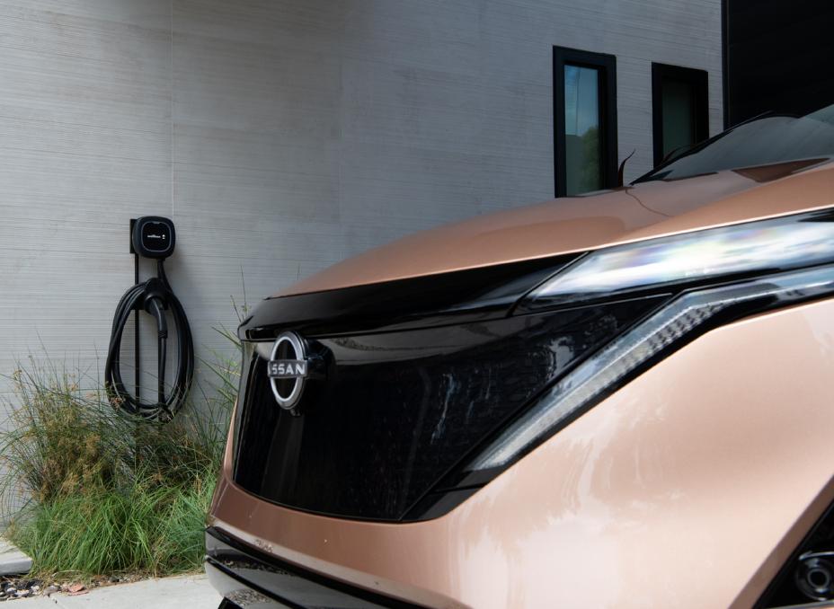 Side profile of 2025 Copper
ARIYA parked in front of an electric
vehicle home charging station.