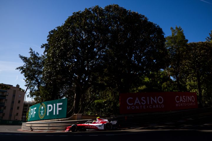 Seitenansicht von Oliver Rowland während des Monaco-E-Prix-Wochenendes auf der Rennstrecke am Steuer des Wagens mit der Startnummer 1, im Hintergrund ist zwischen den Bäumen das Schild des „Casino Monte Carlo“ zu sehen.
