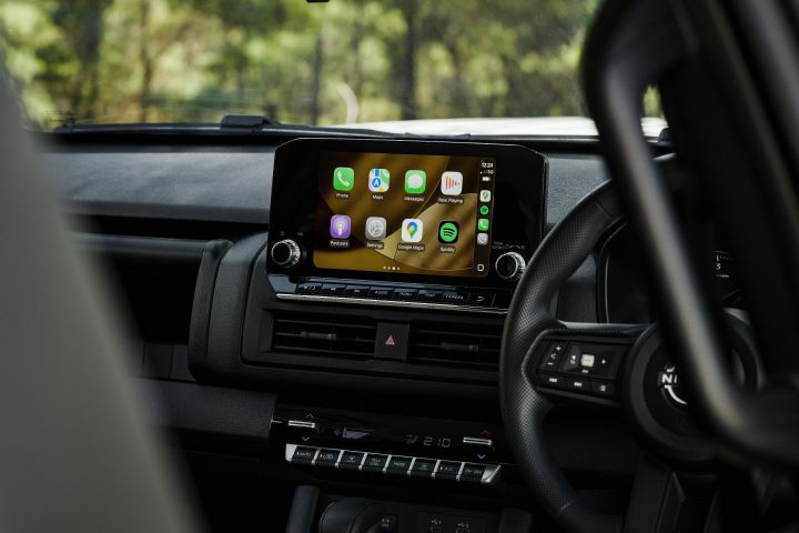 2026 Nissan Navara SL dual cab ute finished in Alpine White showing the infotainment display with smartphone app icons, climate controls and part of the steering wheel.