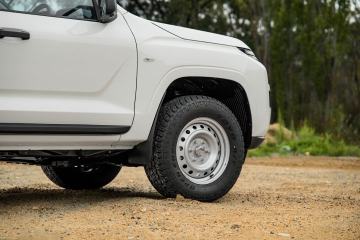 2026 Nissan Navara SL dual cab ute finished in Alpine White detailed at the front wheel section, showing the steel wheel, tyre tread, side step and lower fender design.