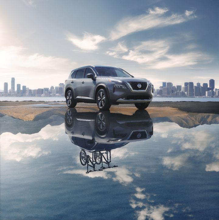 An image of a Nissan Rogue with an alternate image of it in a lakes reflection