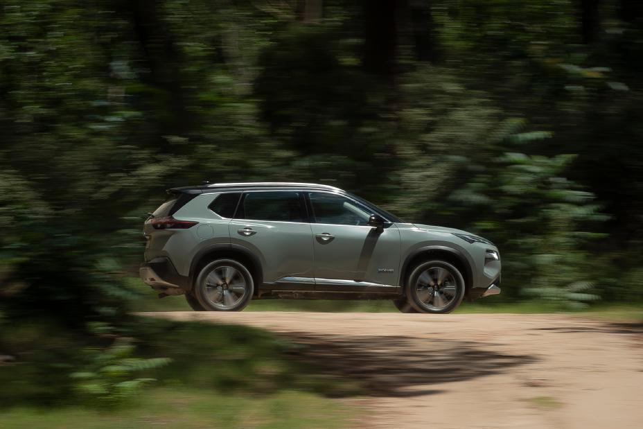 Auto Nissan verde manejando rápido en un camino de tierra