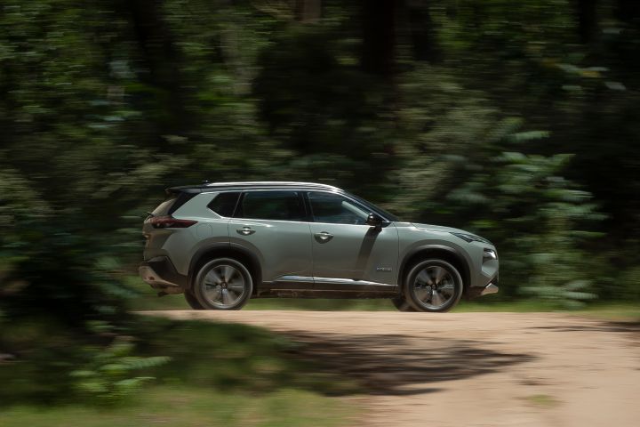 Auto Nissan verde manejando rápido en un camino de tierra