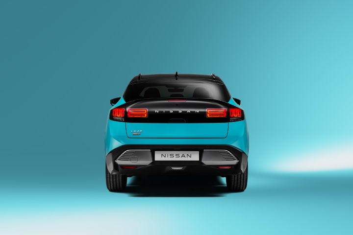 Vue directe de l'arrière de la nouvelle Nissan LEAF bleu turquoise, avec les feux arrière allumés, dans un environnement de studio également bleu turquoise.