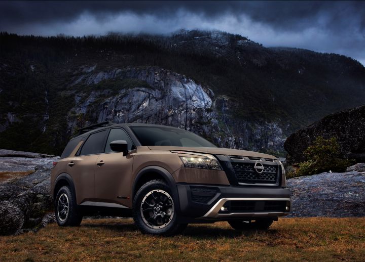 Front left 3/4 image of a Nissan Pathfinder with dark clouds and rocks behind