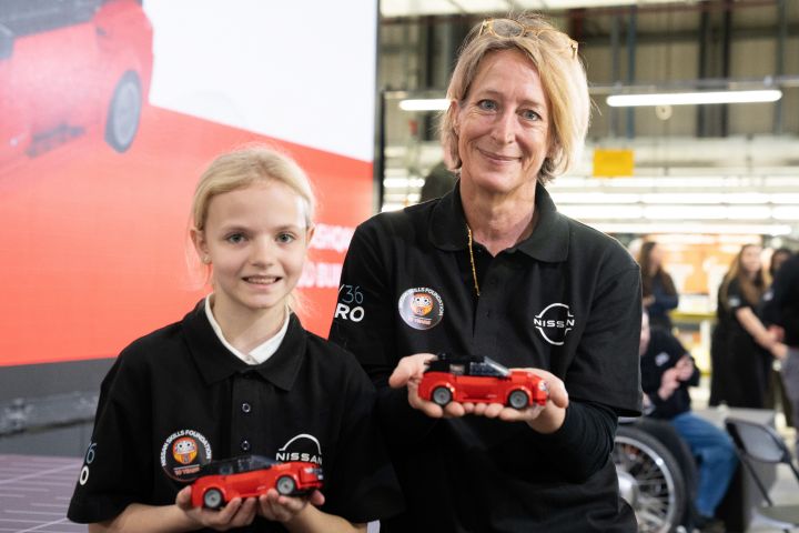 Friederike Kientz standing with a school child both holding a small LEGO Nissan Qashqai.
