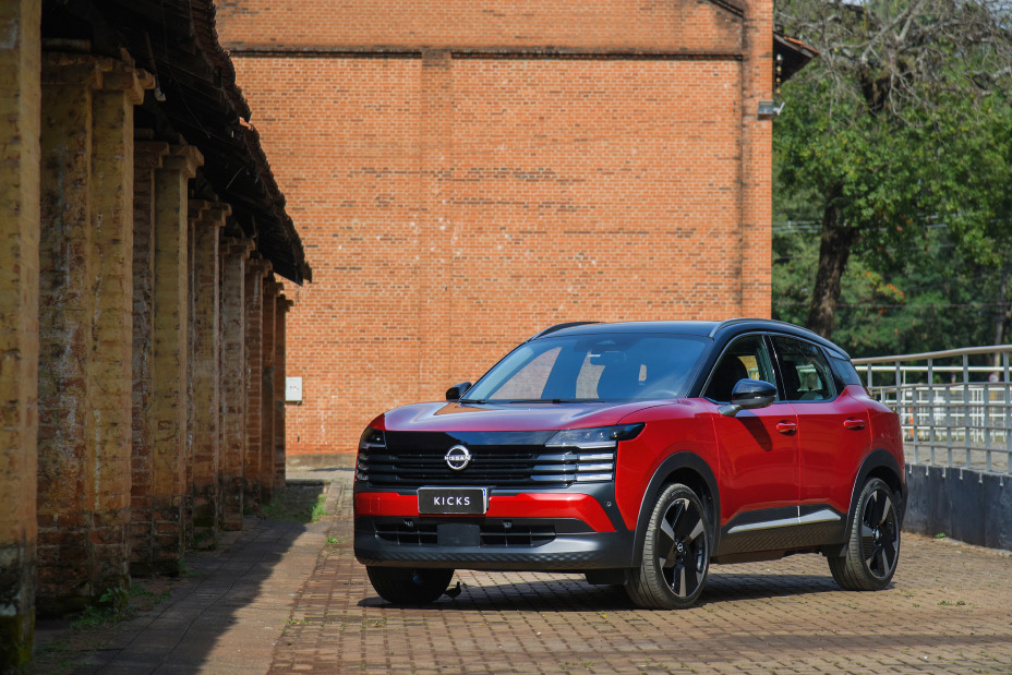 SUV Nissan Kicks vermelho estacionado em área externa com paredes de tijolos ao fundo