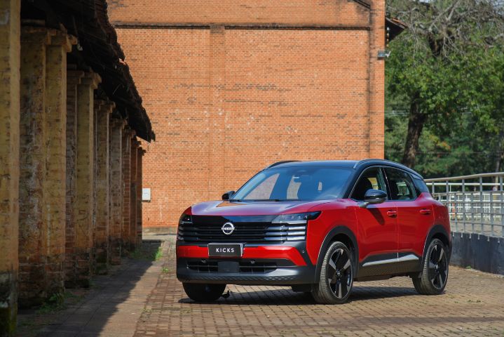 SUV Nissan Kicks vermelho estacionado em área externa com paredes de tijolos ao fundo