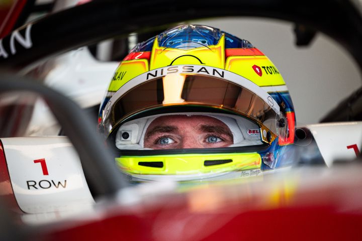 Nahaufnahme von Oliver Rowland mit aufgesetztem Helm und aufgeklapptem Visier in seinem Nissan Formel E Rennwagen