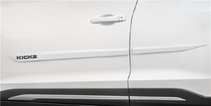 Detalhe da lateral de um Nissan Kicks branco, exibindo um friso de porta com acabamento em Cinza Satin e o nome 'KICKS' em destaque