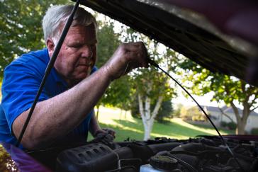 A man is working on a car under the hood.