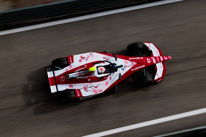 Carro de corrida da Equipe Nissan Fórmula E na cor vermelha fazendo uma curva na pista de corrida