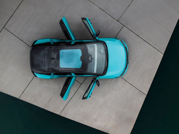 Blick aus der Vogelperspektive auf einen türkisen Nissan LEAF mit Glasdach und vier geöffneten Türen