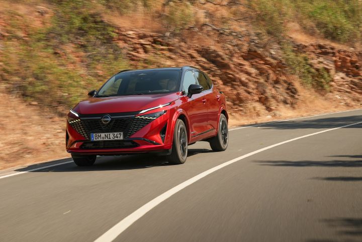 Nieuwe Nissan Qashqai in de kleur Fuji Sunset Red, van de voorzijde gezien, rijdend in een bocht