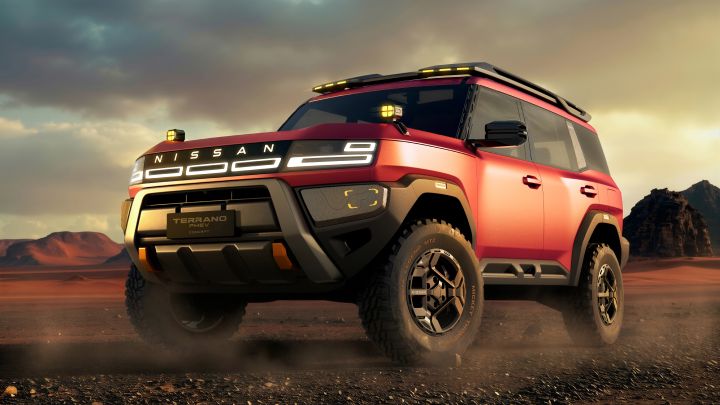 A red Terrano PHEV Concept driving at a front three-quarter angle across a rocky, sandy landscape under a dramatic sunset sky, with distant mountains in the background.