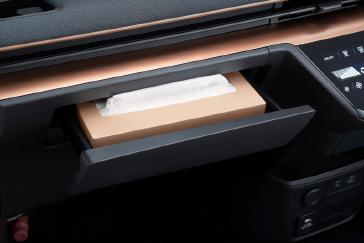 「日産サクラ」の助手席前方にあるインパネ収納を撮影した画像。黒いダッシュボードに組み込まれた収納スペースが開いた状態で写り、小物が収納されている。撮影は正面やや左向きから行われている。