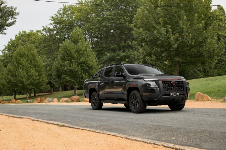 2026 Nissan Navara PRO-4X finished in Boulder Grey shown from a wide front three-quarter angle on a curved park road.