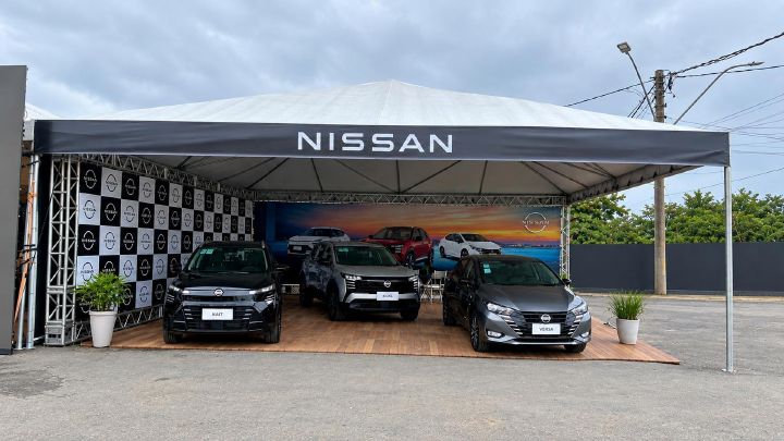 Estande da Nissan na Exapicor com três veículos em exposição: o novo Nissan Kait, o novo Nissan Kicks e o Nissan Versa. Os carros estão posicionados sob uma tenda com a marca Nissan em destaque, em um espaço preparado para receber os visitantes da feira.