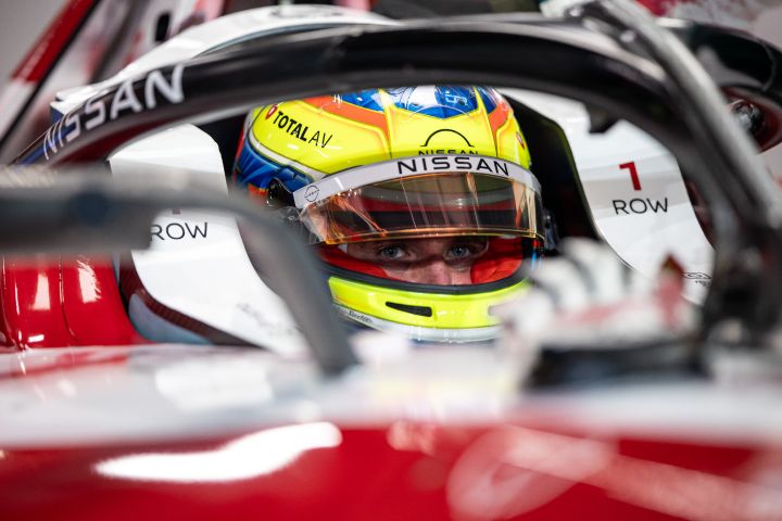 Oliver Rowland mit seinem gelben Helm und hochgeklapptem Visier sitzt im Nissan e‑4ORCE 05 mit der Startnummer 1 und wartet in der Teamgarage darauf, auf die Strecke zu gehen.