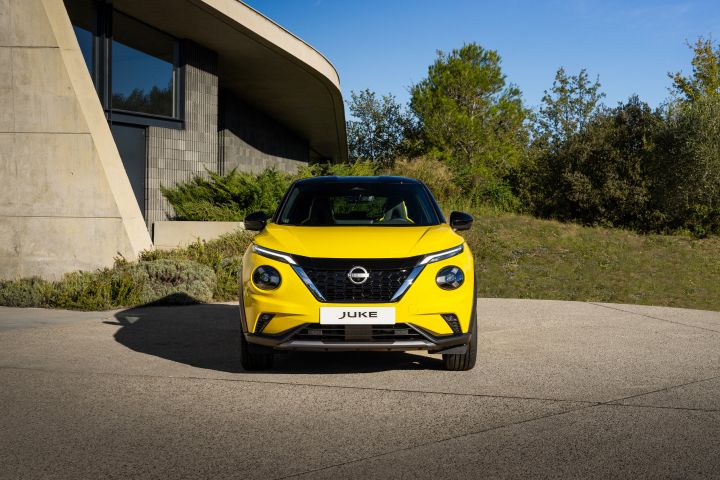 Gelber Nissan Juke Front auf hellem Untergrund vor hellem Gebäude und Wiese