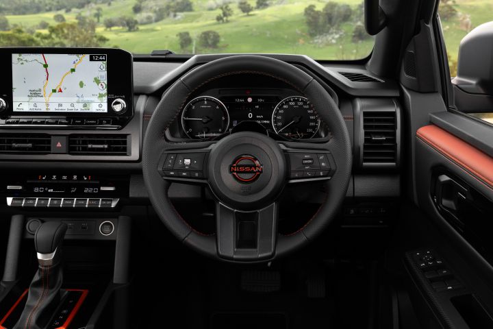 2026 Nissan Navara PRO-4X finished in Boulder Grey focusing on the driver’s area with steering wheel, digital instrument display and infotainment screen.