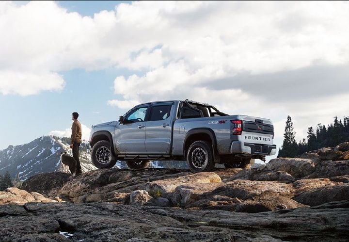 Nissan Frontier V6 PRO-4X NISMO® gris con persona al lado en cima de montaña