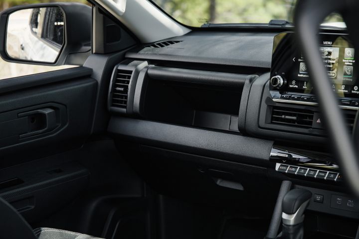 2026 Nissan Navara SL dual cab ute finished in Alpine White viewed from the passenger side, showing the dashboard shelf, air vent, door trim and infotainment screen edge.