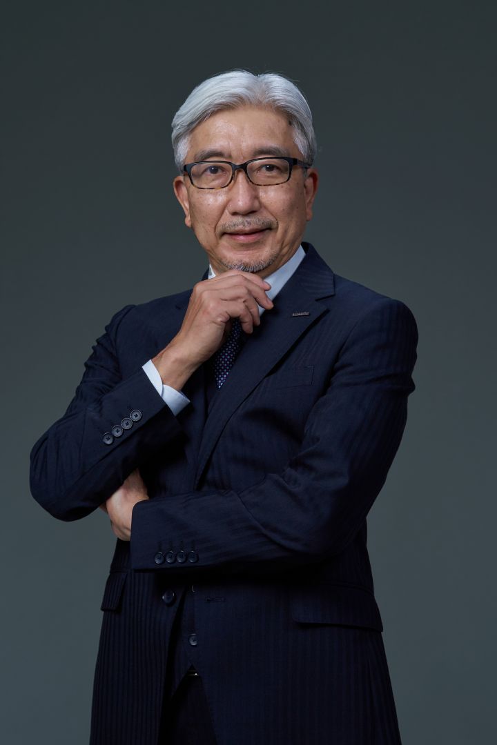 Portrait of Mitsuro Antoku placing his hand on his chin (suit, tie and NISSAN corporate pin)
