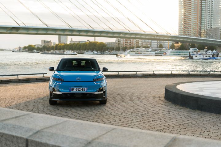 Frontale Ansicht eines blauen Nissan Micra vor Wasser und Brücke in Rotterdam