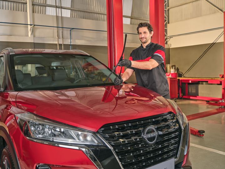 Reparador instala uma palheta de limpador de para-brisa em um modelo antigo do Nissan Kicks