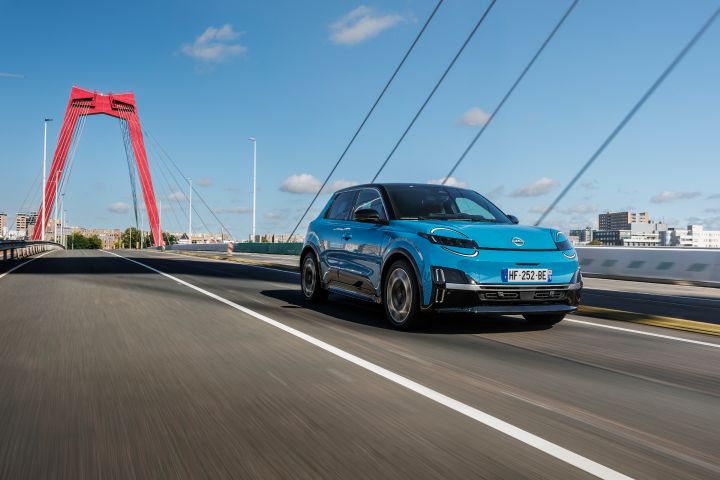 3/4 Front-Fahraufnahme eines blauen Nissan Micra auf einer Brücke mit roten Pfeilern