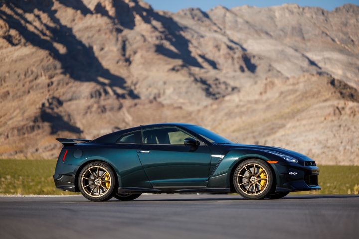 Right side profile view of the Midnight Purple 2024 GT‑R T-spec Takumi parked on a road with mountains behind.