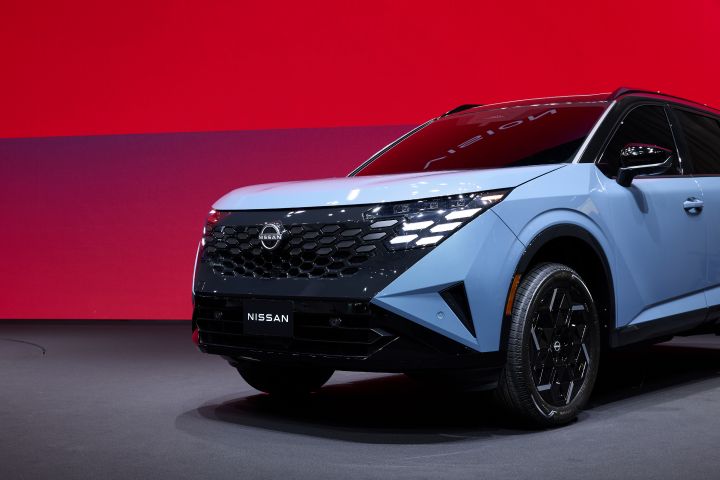 Angled view of the first half of the 2027 Nissan Rogue Hybrid e‑POWER on a stage with a red screen behind.