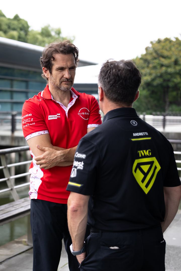 Hochformatfoto von Tommaso Volpe, Geschäftsführer und Teamchef des Nissan Formula E Teams, und Roger Griffiths, Teamchef von Andretti Formula E, im Gespräch, wobei Volpe die Arme verschränkt hat und Griffiths mit dem Rücken zur Kamera steht.